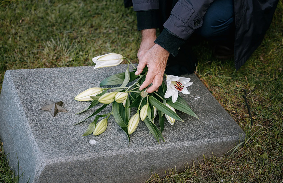 About Us - Laying Flowes on Grave Laying flowers on a Tombstone